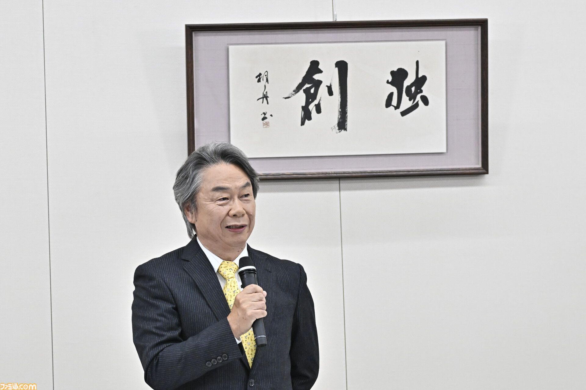 기자회견장 ‘독창’ 편액 앞에서 마이크를 쥐고 온화한 표정으로 이야기하는 미야모토 시게루.